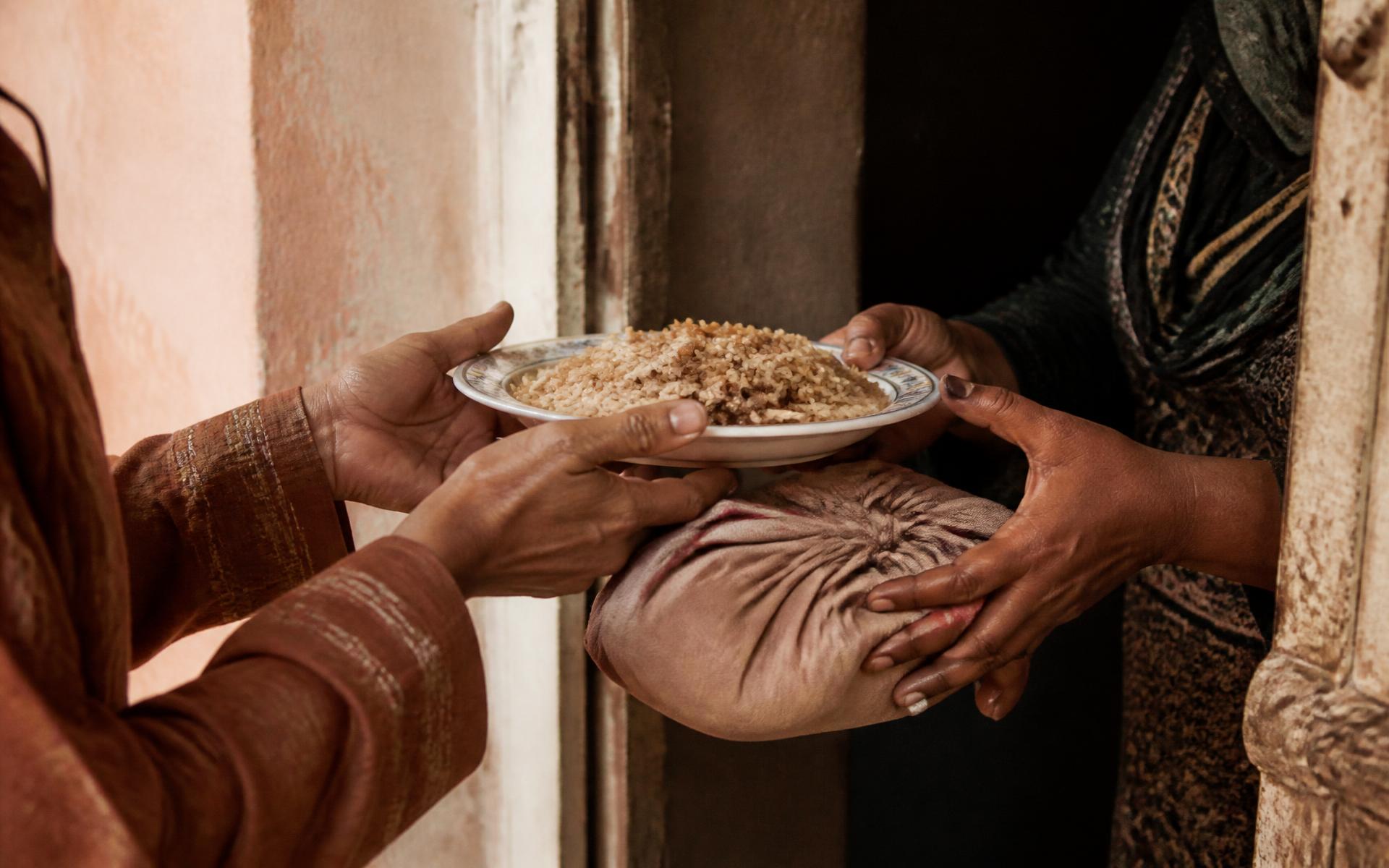 two pairs of hands passing a plate of food across a doorway